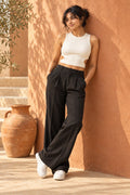 Side Cut Out Rib Tank Top in Coconut Milk – leaning on a terracotta wall